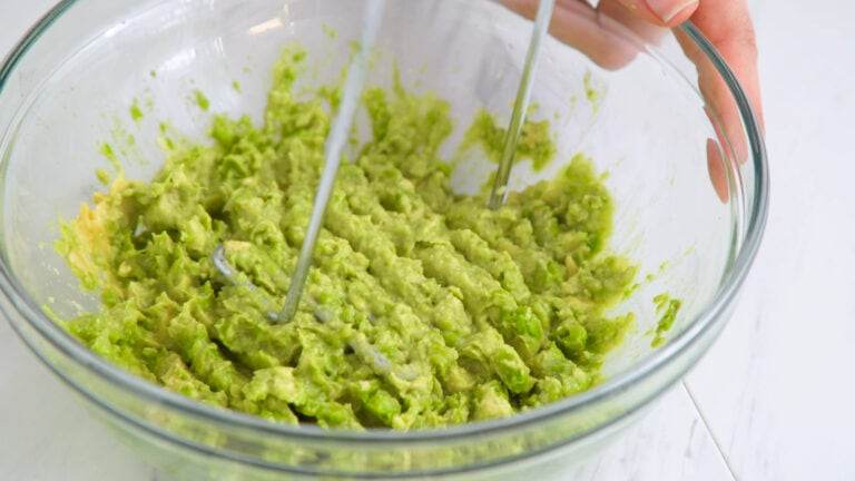 Using a masher to mash your guacamole ingredients.