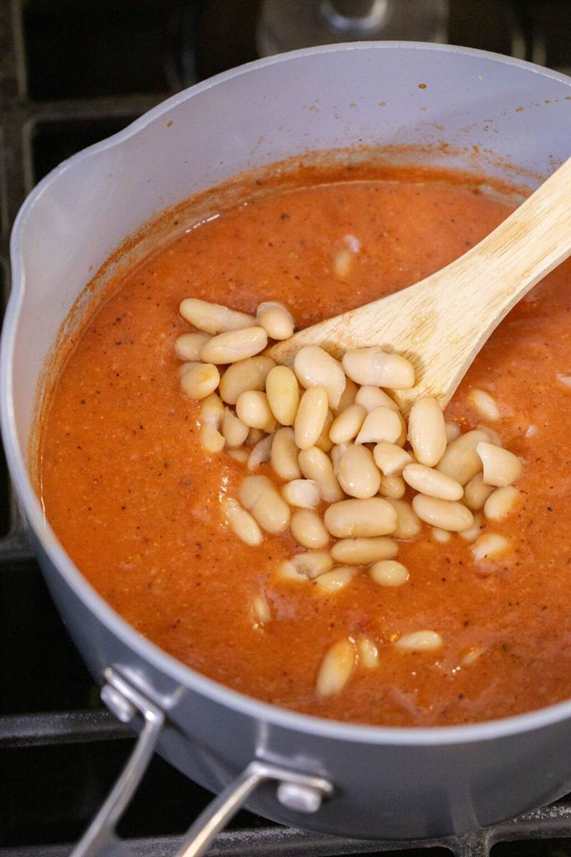 Adding additional whole cannellini beans to blended 3-ingredient white bean tomato soup.