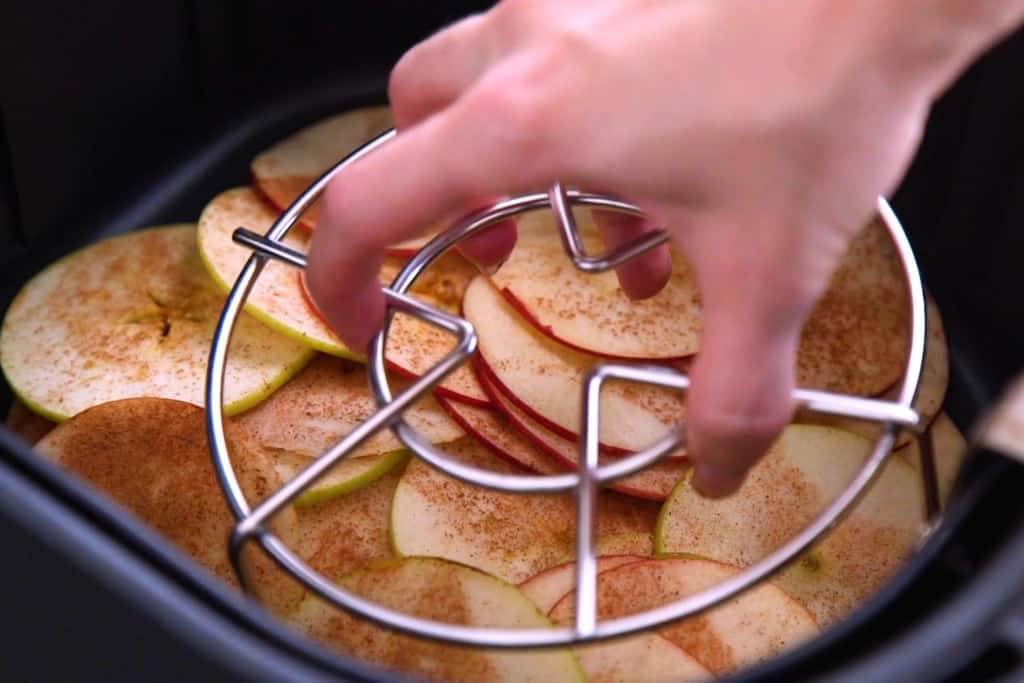 Place a metal rack/trivet on top of apple chips in air fryer while they cook. Flip them every 5 minutes or so.
