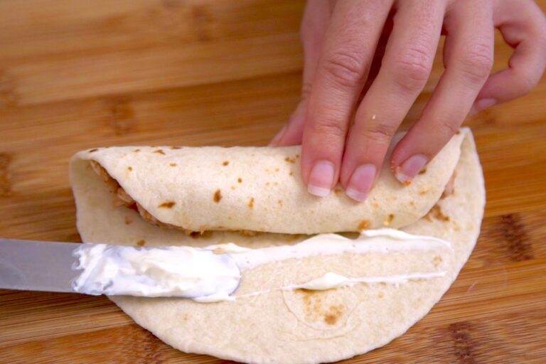 Roll up each chicken taquito tightly. Spread sour cream (or refried beans) along the inside edge of the tortilla to seal it shut.