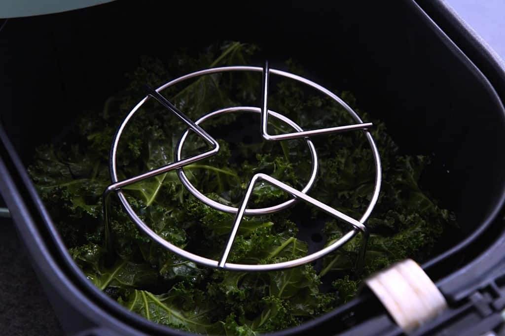 If you have one, place a metal rack/trivet on top of kale while it cooks in the air fryer.