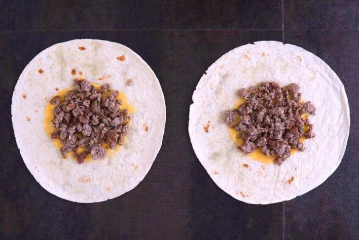 Lay large tortillas flat, spread nacho cheese sauce in the middle, and top with cooked breakfast sausage.