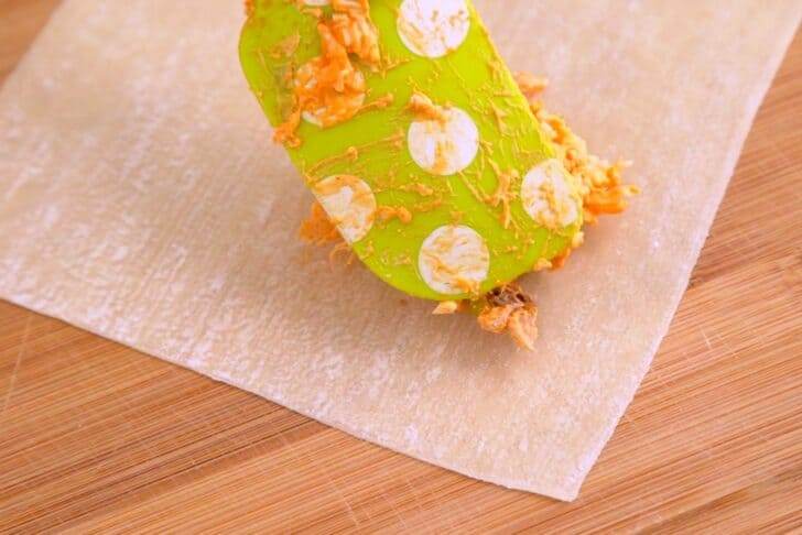 Arrange egg roll wrapper in a diamond shape, add filling mixture, and roll up tightly.