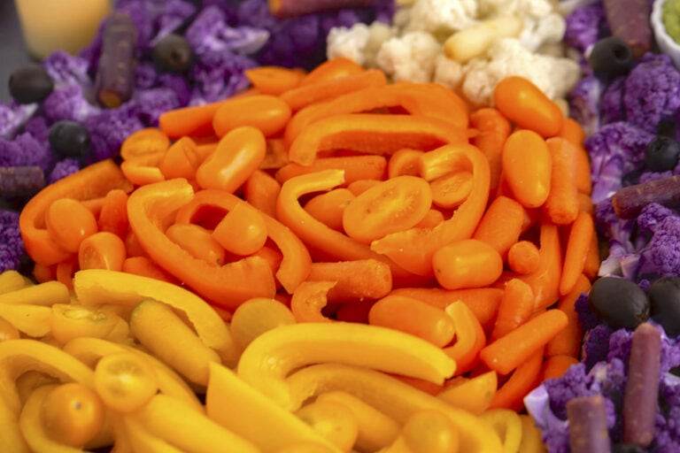 Orange layer of candy corn vegetable tray with baby carrots, orange bell pepper slices, & orange mini tomatoes.