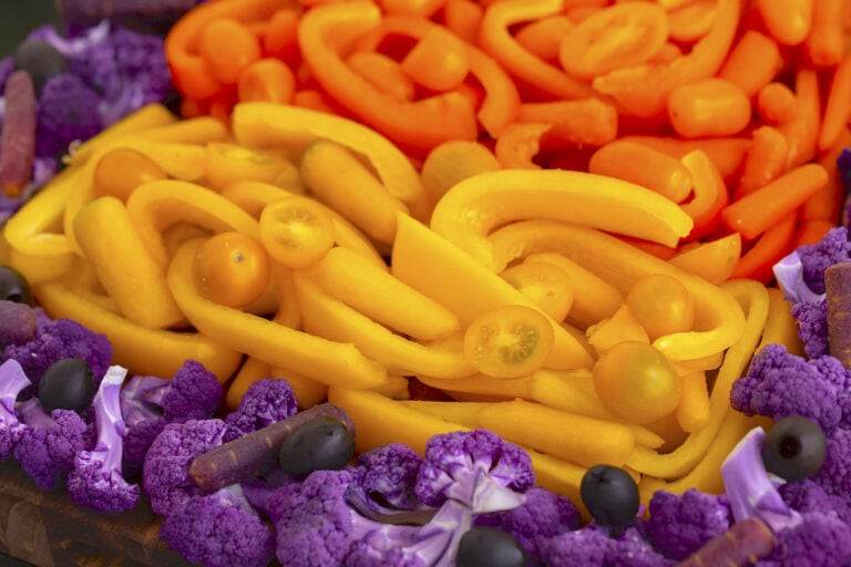 Yellow layer of candy corn snack board with yellow carrots, peppers, & tomatoes.