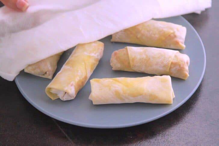 Cover assembled egg rolls with a damp cloth to prevent drying out.