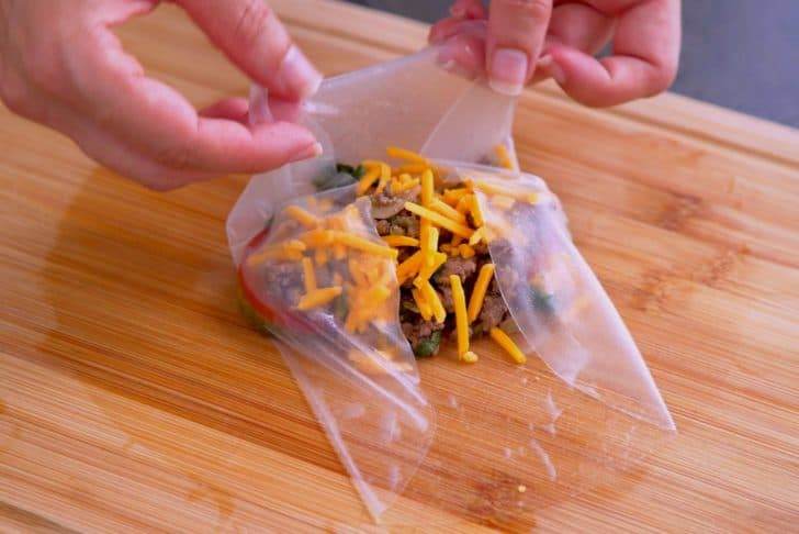 Layer filling ingredients onto wet rice paper, then fold in edges and roll up snugly.
