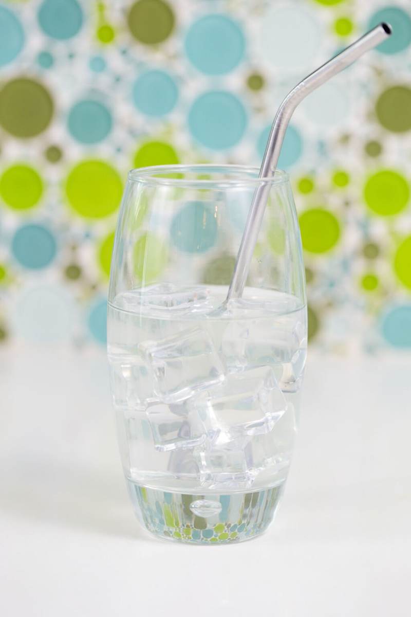 A glass of coconut water with ice on a white table.