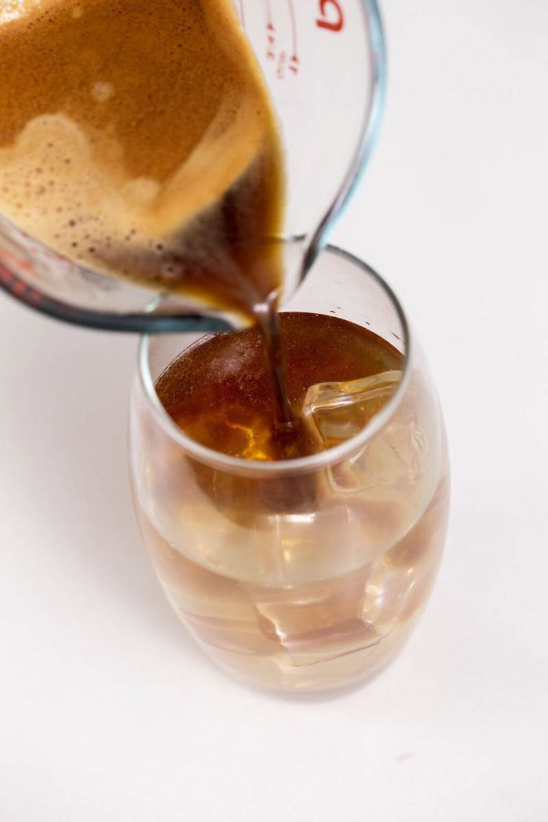 Pouring espresso into the glass with the orange juice and iced coconut water