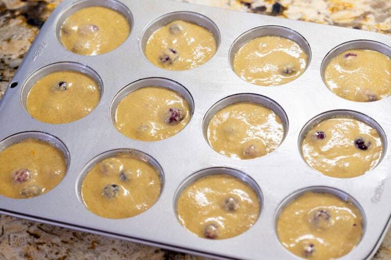 Cranberry orange muffin batter scooped into a muffin tin, not yet baked.