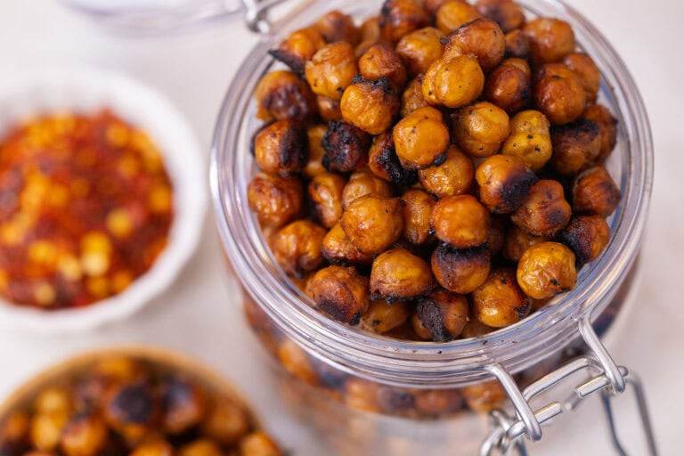 Glass jar filled with crunchy Asian-style roasted chickpeas on a white countertop.