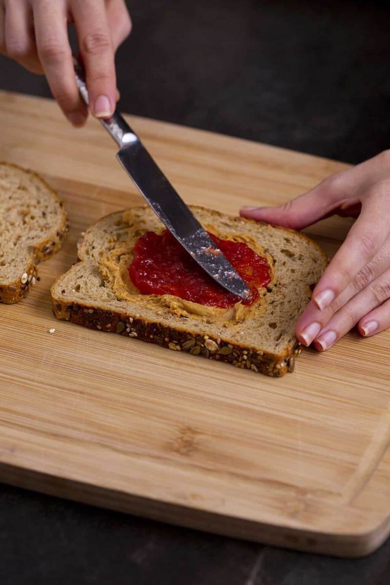 Spread peanut butter and then jelly onto the same slice of bread, keeping both spreads in the center of the bread.