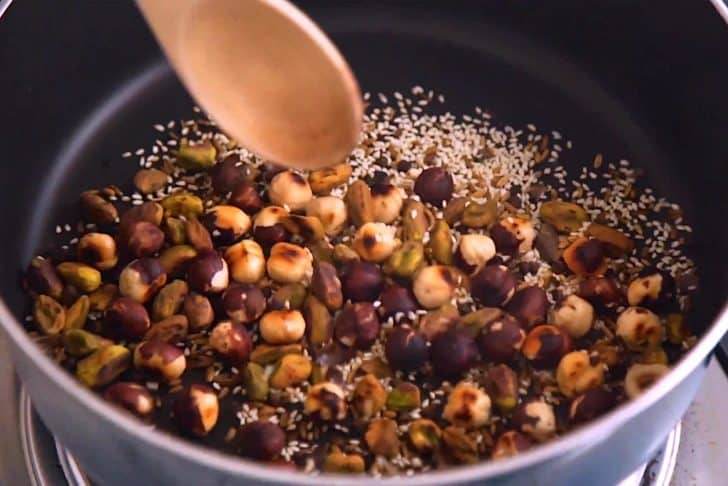 Stir nuts and seeds regularly, monitoring to make sure they don't burn.