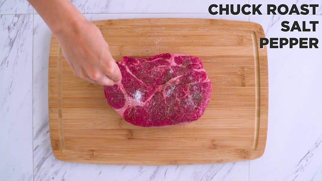 Seasoning the raw chuck roast with salt and pepper