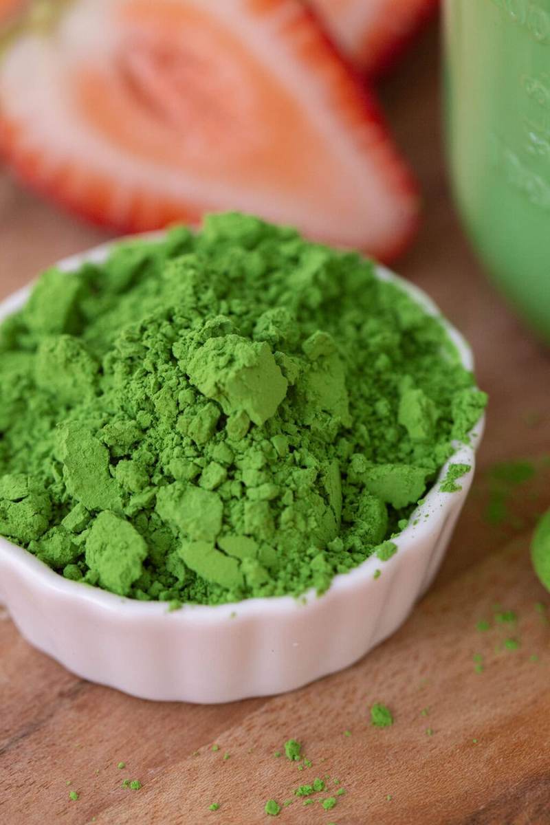 A small white bowl filled with bright green matcha powder.