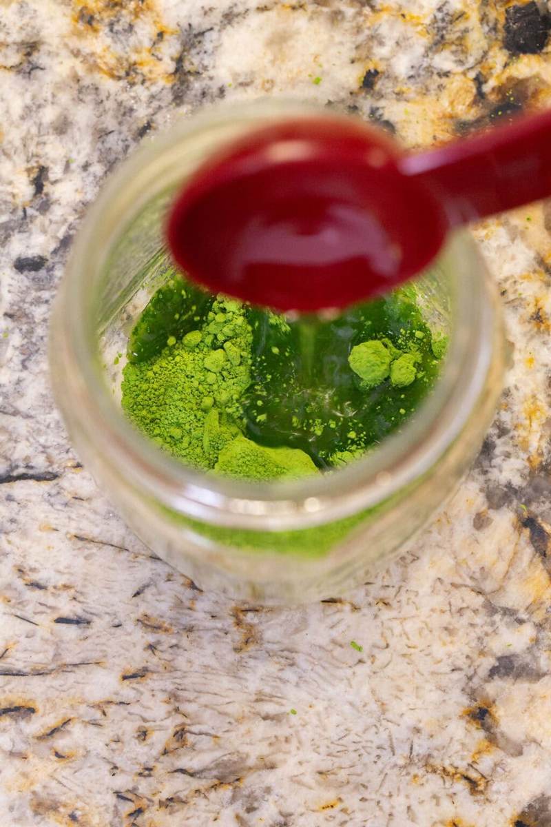 An overhead shot of adding optional sweetener to the iced matcha latte.