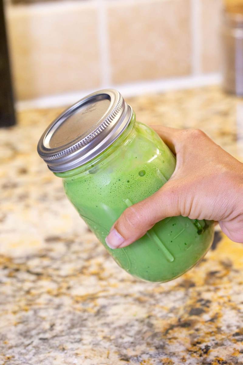 A shot of shaking the sealed glass jar with the iced matcha latte ingredients inside.