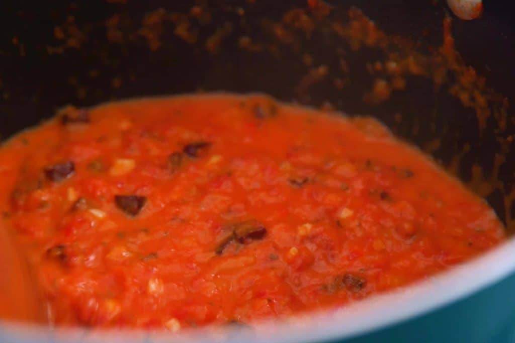 Simmer tomato meat sauce for 45-60 minutes, mashing as you go.