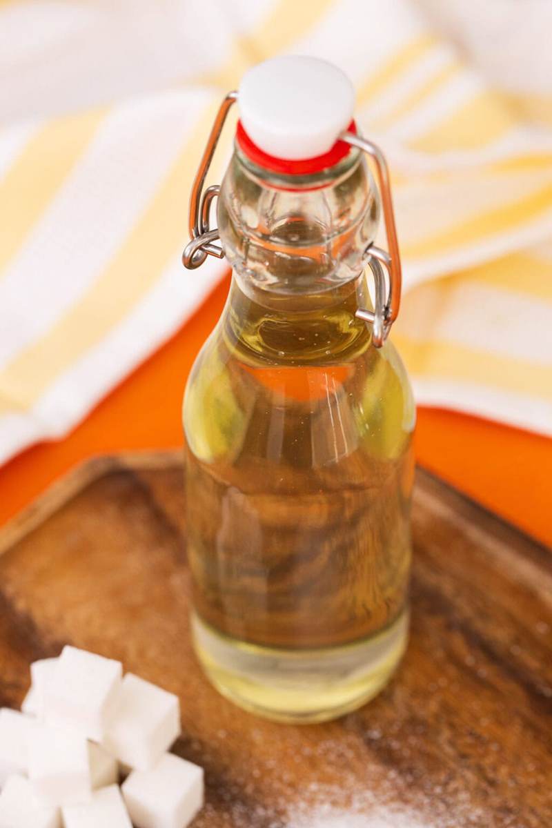 Simple syrup in a bottle next to a pile of sugar cubes