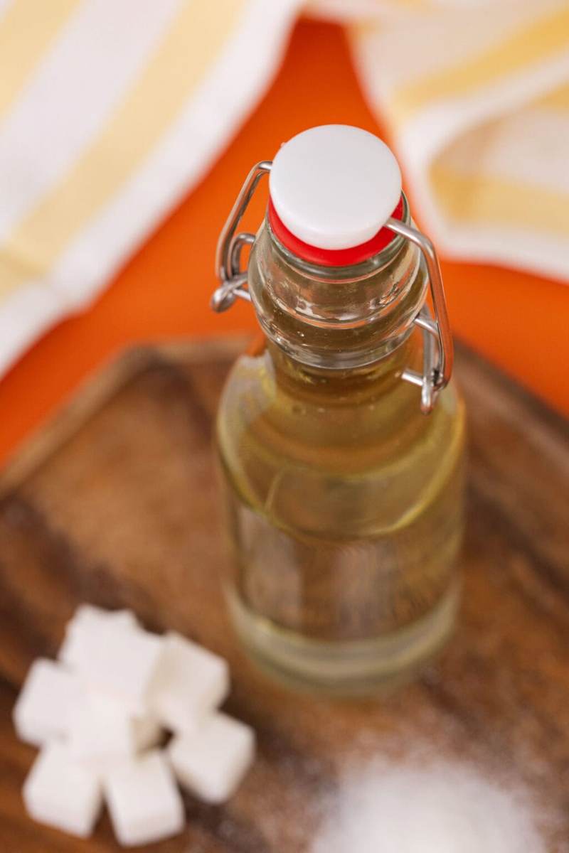 Simple syrup in a bottle on a table next to a pile of sugar cubes