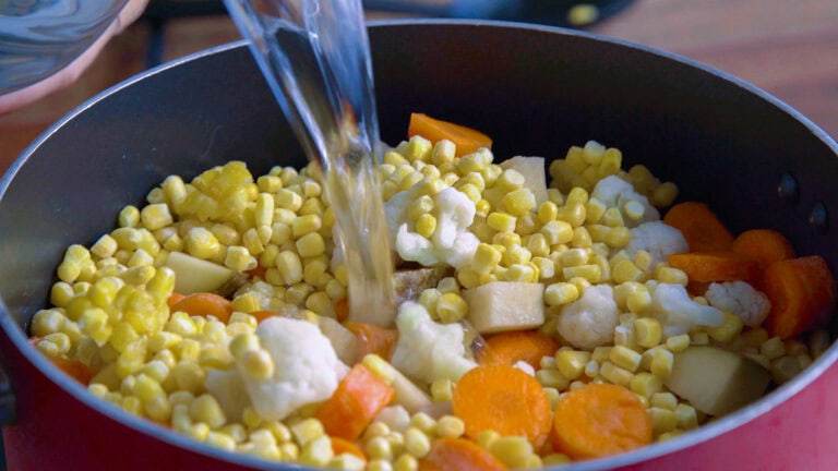 Preparing the soup by pouring water into a pot with the ingredients.
