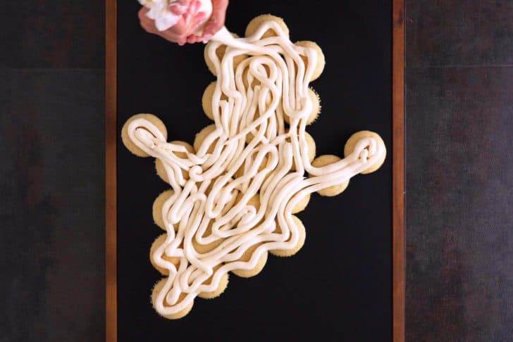 Add white frosting liberally to cover entire surface of Halloween cupcake cake—either squeeze it from a decorating bag, or spread it on directly from the tub.