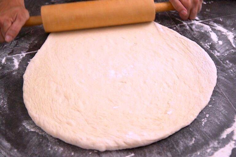 Roll the dough until it's around 1/4-inch thick, lifting and rotating the dough as you go to create a round pizza crust.
