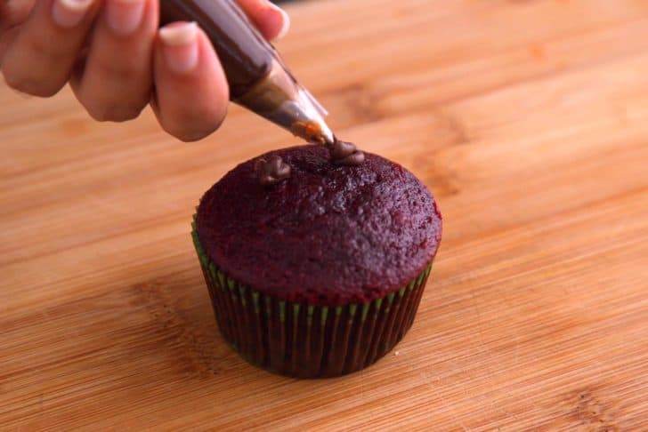 Onto cooled cupcakes, add 2 dots of frosting as glue for large candy eyes.