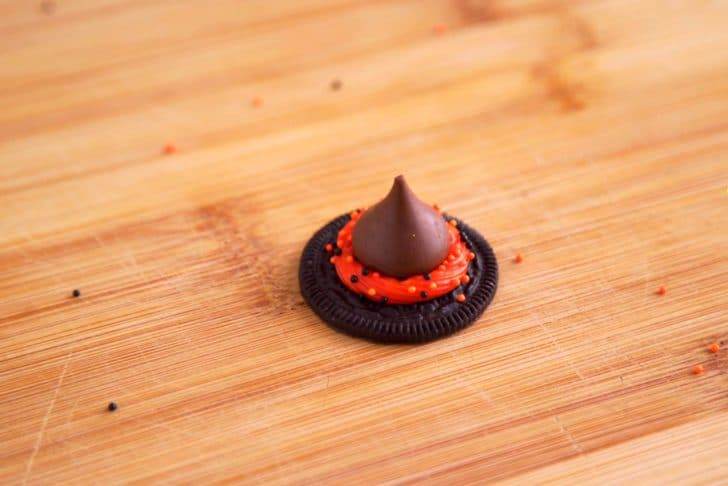To make hat toppers, add a dollop of frosting on top of a single Oreo cookie. Add festive sprinkles if desired, then press a chocolate kiss into the frosting so it sticks.