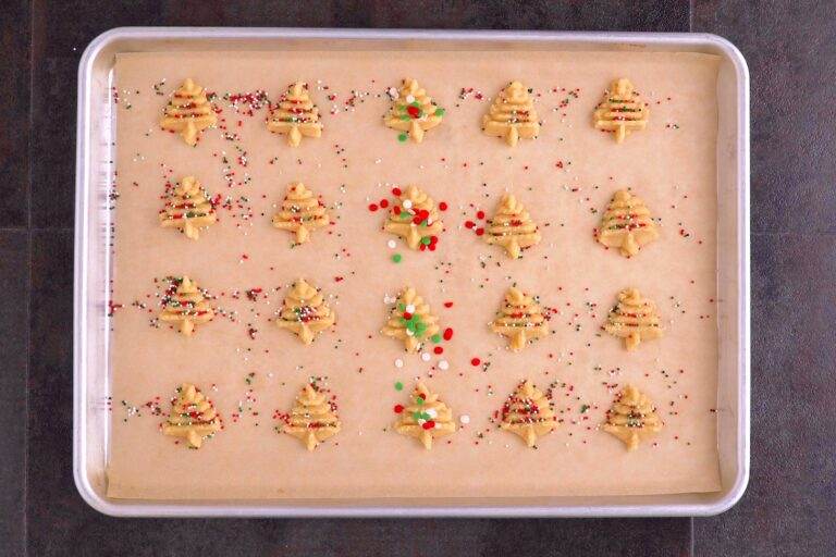 Transfer pressed spritz cookies onto a baking sheet lined with parchment and add festive sprinkles.