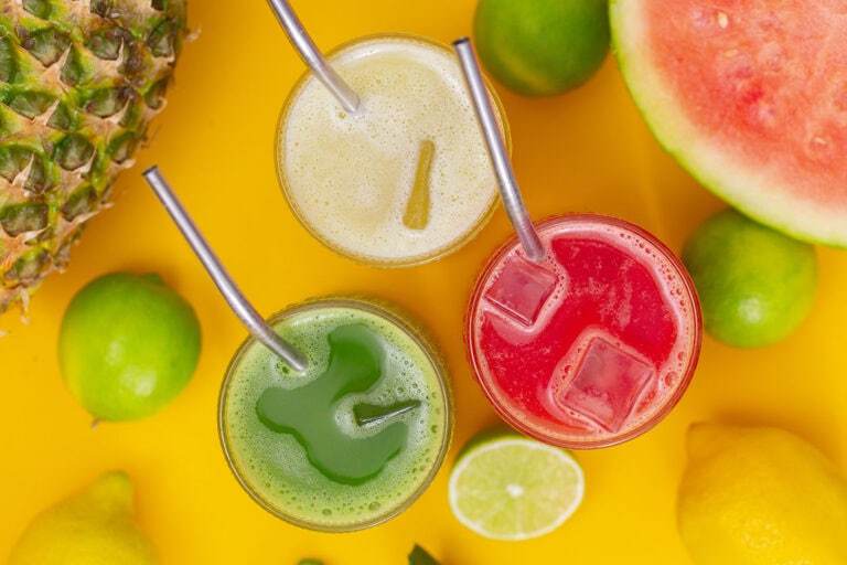 An overhead photo of three glasses of agua fresca, cucumber, pineapple, and watermelon flavors.
