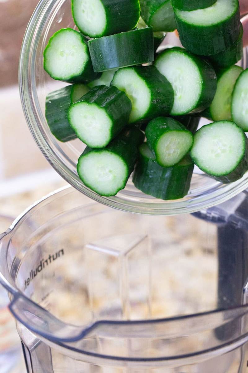 Chopped cucumber being poured into a blender.