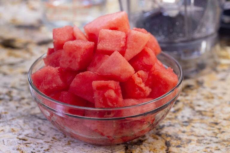 Cubed watermelon in a glass bowl on a counter.