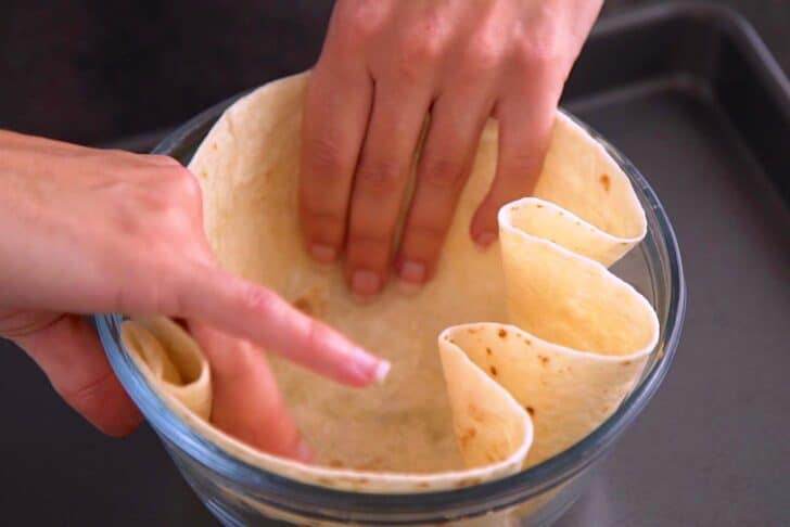 Press tortilla into a deep (1-quart) oven safe bowl, folding and pleating the edges to fit the shape of the bowl.