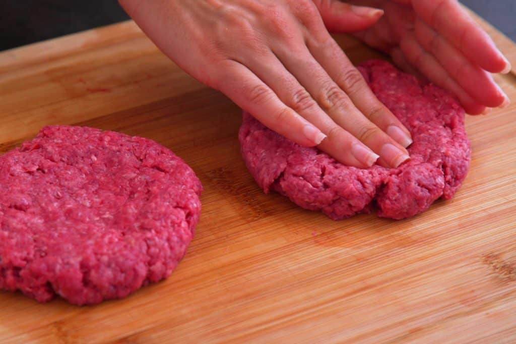 Shape meat gently, adding a shallow dimple in the center of each patty to prevent shrinkage and doming.