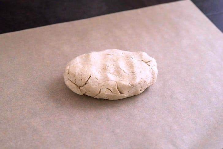 Knead dough with hands until pliable, then place onto a sheet of parchment.