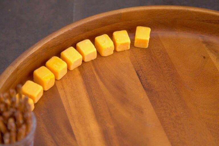 Arrange cheese cubes & cheese slices to fill the edges of a round charcuterie board.