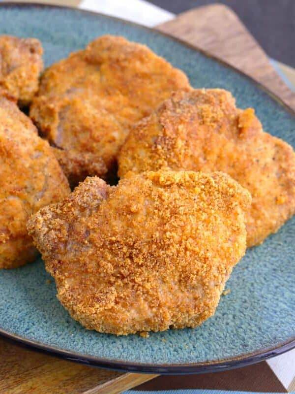 Crispy Air Fryer Pork Chops on a blue plate on top of a wooden cutting board