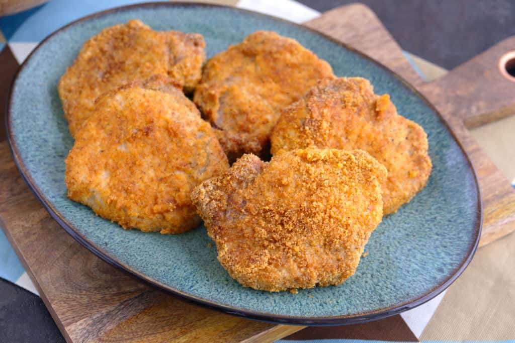 Crispy Air Fryer Pork Chops on a blue plate on top of a wooden cutting board
