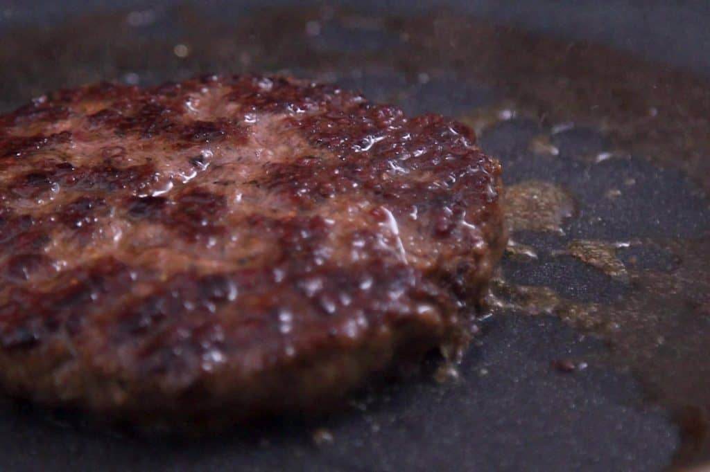 Cook burger patties to desired doneness, adding cheese to melt after flipping.