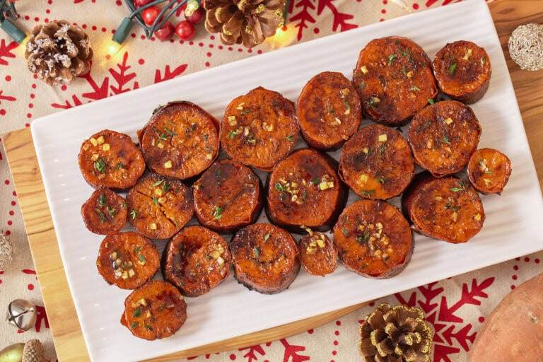 an overhead shot of sliced, roasted sweet potatoes on a white plate.