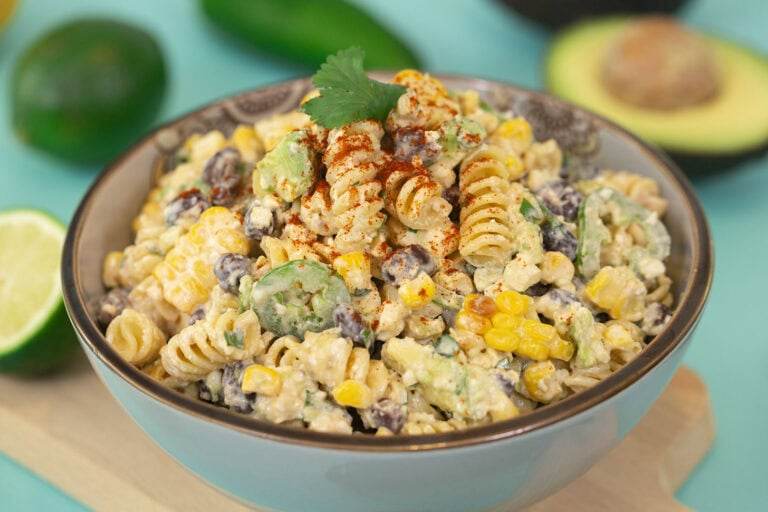 A side-profile shot of the recipe Easy Mexican Street Corn Pasta Salad on a blue table.