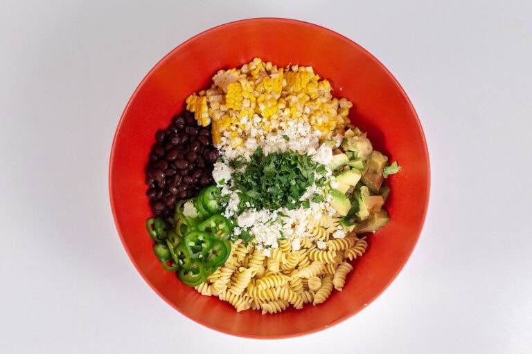 An overhead photo of a large red mixing bowl containing all the ingredients for the salad, unmixed.