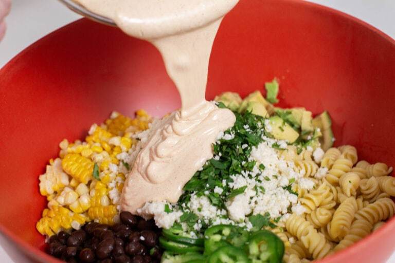pouring her Mexican Crema into the large mixing bowl with the rest of the ingredients.