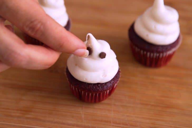 Carefully and gently press mini chocolate chips into the marshmallow frosting poof as the ghost's eyes.