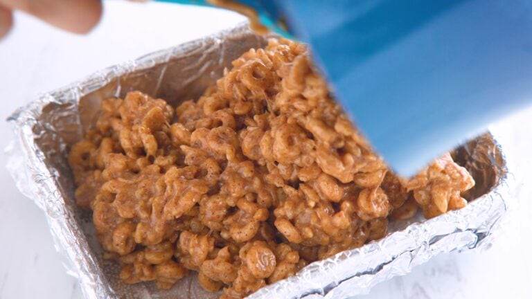 transferring homemade rice krispy treat mixture to a baking dish to refrigerate