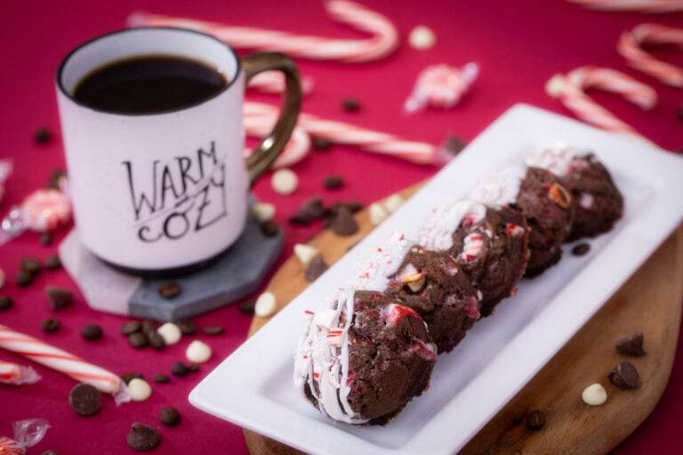 Peppermint mocha cookies on a red table next to a cup of coffee surrounded by christmas decor