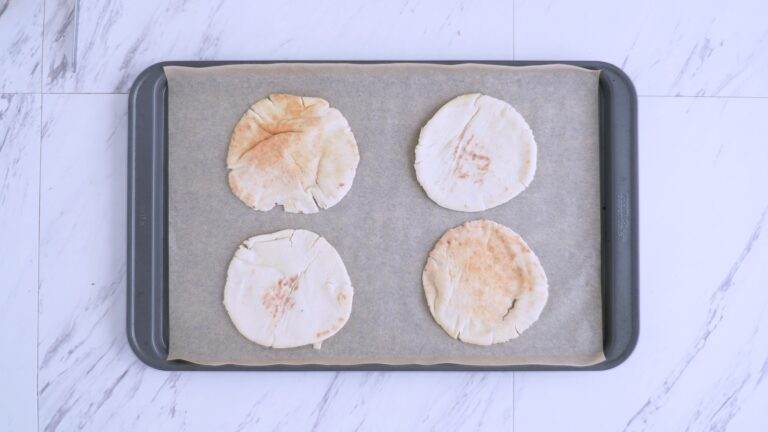 Pita halves laid out on a baking sheet lined with parchment paper