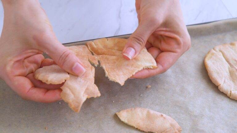 Breaking apart the toasted pita halves to make easy homemade pita croutons