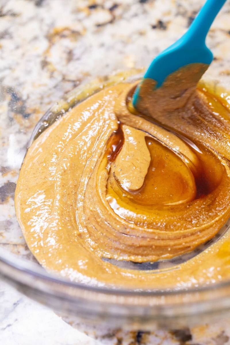 Using a spatula to stir together the peanut butter, honey, vanilla extract, and salt in a glass mixing bowl.